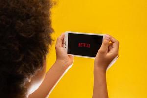 Ribeirao Preto, Sao Paulo Brazil Circa November 2019 Opening Netflix application icon on iPhone 8 Plus boy resting with her cell phone in her hands and the Netflix logo in the screen. photo