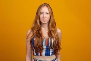 Portrait of beautiful cheerful redhead girl with flying hair smiling laughing looking at camera over yellow background. photo