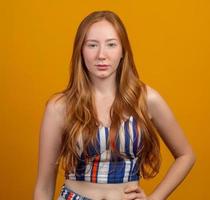 Portrait of beautiful cheerful redhead girl with flying hair smiling laughing looking at camera over yellow background. photo