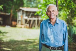 Portrait of smiling beautiful older male farmer. Elderly man at farm in summer day. Gardening activity. Brazilian elderly man. photo