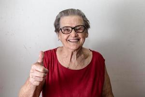 Beautiful old woman with two tumbs up. Cheerful caucasian senior showing two thumbs up on white background. photo