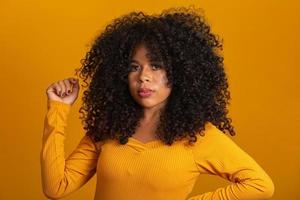 joven mujer afroamericana con cabello rizado mirando a la cámara y sonriendo. linda chica afro con cabello rizado sonriendo mirando a la cámara. foto