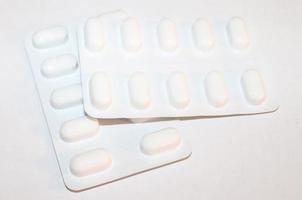 Pharmacy drugstore concept. Packs of white pills packed in blisters with copy space isolated on a white background. Focus on foreground, soft bokeh. photo