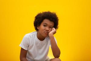 Close up ten year old boy looking to the right with bored facial expression, Isolated on yellow background photo