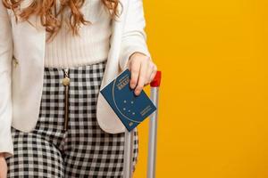 Beautiful redhead curly-haired girl in travel. Next trip. Girl holding Brazilian passport. On yellow. photo