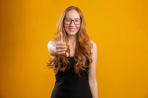 Close up photo of pretty foxy lady raising thumb up expressing agreement wear checkered casual shirt isolated yellow color background. Redhead girl. Okay.