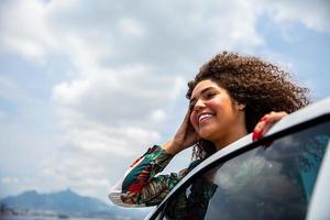 Beautiful african american girl with an afro hairstyle smiling side a car photo