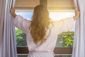 gente y concepto de esperanza - cerca de una mujer feliz abriendo cortinas de ventana foto