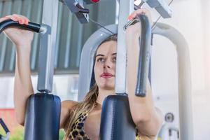 Girl training pectoral in gym apparatus photo