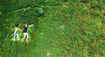 happy couple together in love isolated laying in green nature field on summer day. Top view fun in relationship couple copypaste background photo