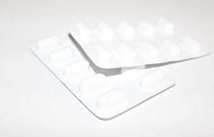 Pharmacy drugstore concept. Packs of white pills packed in blisters with copy space isolated on a white background. Focus on foreground, soft bokeh. photo