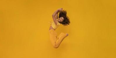 Side view of afro hair woman in zero gravity or a fall. Girl is flying, falling or floating in the air. Side view of person. Over yellow background. Getting sucked up. Woman being abducted. photo