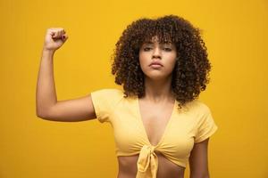 podemos hacerlo puño de mujer de poder femenino. mujer víctima del racismo. abuso en el trabajo. el poder femenino. empoderamiento femenino. la fuerza de las mujeres. fondo amarillo foto