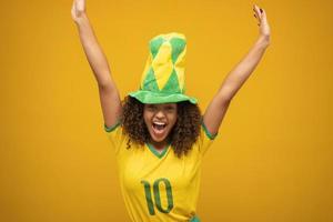 partidario de brasil. hincha brasileña celebrando un partido de fútbol con fondo amarillo. colores de brasil. foto