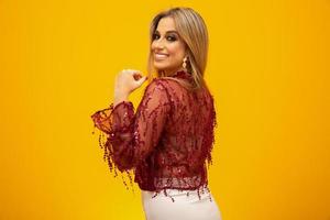 Beautiful blonde woman in fashion theme. Young beautiful woman wearing fashion t-shirt standing over yellow background with smile on face, natural expression. Laughing confident. photo