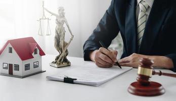 Judge gavel and house model on the table. Man signing in document. Real Estate Lawyer photo