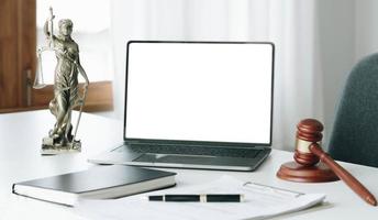 Workspace of lawyer with laptop blank white screen and law wooden gavel, and brass scale of judge. courtroom legal concept. photo