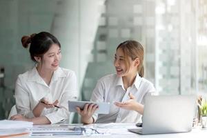 Two asian business woman work together to get the job done at the office. photo