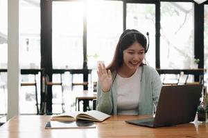 una mujer asiática que usa auriculares estudia en línea viendo un podcast de seminario web en una computadora portátil escuchando un curso de educación de aprendizaje conferencias telefónicas, concepto de aprendizaje electrónico. foto