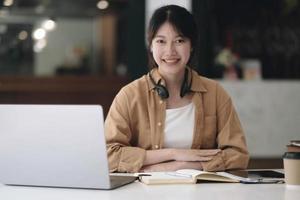feliz joven estudiante asiática con auriculares mirando la cámara web, mirando la cámara, durante una reunión virtual o una videollamada.