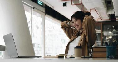 Freelance business women casual wear using tablet working call video conference with customer in workplace in living room at home. Happy young Asian girl relax sitting on desk do job in internet. photo