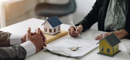 los agentes inmobiliarios explican el documento a los clientes que se ponen en contacto para comprar una casa, comprar o vender el concepto inmobiliario foto