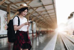 Young traveler woman looking for friend planning trip at train station. Summer and travel lifestyle concept photo