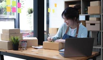 Starting small businesses SME owners female entrepreneurs Write the address on receipt box and check online orders to prepare to pack the boxes, sell to customers, sme business ideas online. photo