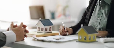 los agentes inmobiliarios explican el documento a los clientes que se ponen en contacto para comprar una casa, comprar o vender el concepto inmobiliario foto