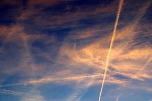 Estelas de condensación de aviones en el cielo azul entre algunas nubes foto