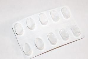 Pharmacy drugstore concept. Packs of white pills packed in blisters with copy space isolated on a white background. Focus on foreground, soft bokeh. photo