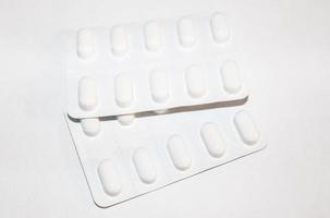 Pharmacy drugstore concept. Packs of white pills packed in blisters with copy space isolated on a white background. Focus on foreground, soft bokeh. photo