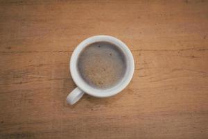 A coffee cup and milk froth are on a wooden background. photo