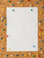 white paper note sheet with blue push pin on cork board photo