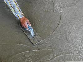 hand using trowel to finish wet concrete floor