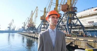 Young male worker of sea harbor in helmet, cargo manager in suit and halmet works outdoor , cranes and sea background photo