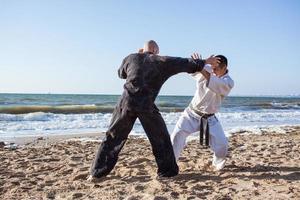 los luchadores de karate están peleando en el ring de boxeo de la playa por la mañana foto