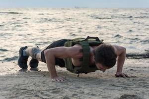 joven atleta barbudo entrenando al aire libre con chaleco ponderado, ejercicio con portador de placa militar foto