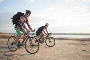 dos jóvenes en una bicicleta de gira con mochilas y cascos en el desierto en un viaje en bicicleta foto