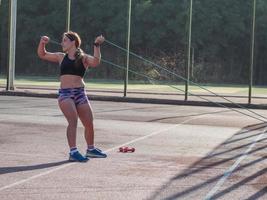 Young strong woman training outdoors in summer time, female professional athlete do exercises in the park photo