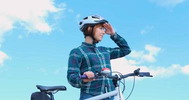 Young woman bicycle rider in helmet in sunny summer day photo