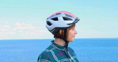 Young woman bicycle rider in helmet in sunny summer day photo