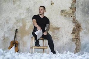 joven con guitarra en una habitación vacía, músico y compositor solo en el estudio foto