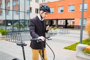 joven hombre de negocios con bicicleta y taza de café o té caminando al aire libre foto