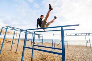 Young fit male training do exercises outdoor on the beach photo