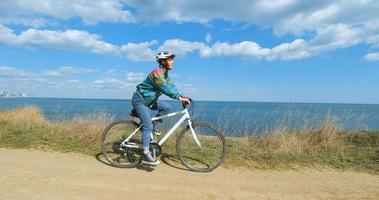 Young woman bicycle rider in helmet in sunny summer day photo