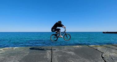 macho joven con monopatín relajándose cerca del mar foto