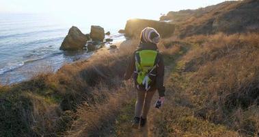 joven viajera con mochila y cámara de cine retro viaja en las montañas de otoño cerca del mar foto