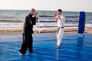 karate fighters are fighting on the beach boxing ring in morning