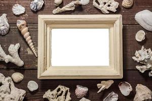 Blank photo frame with shells on wooden table